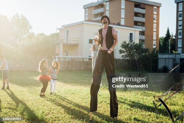 male artist juggling balls while standing with stilts on grass - styltor bildbanksfoton och bilder