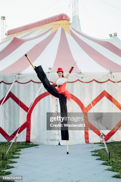 female artist holding hand fan while standing with stilts in front of tent - stilt stock pictures, royalty-free photos & images