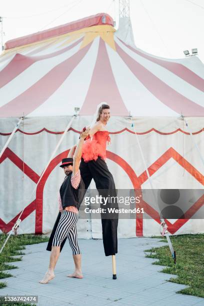 male acrobat holding hand of female artist while practicing on footpath - styltor bildbanksfoton och bilder