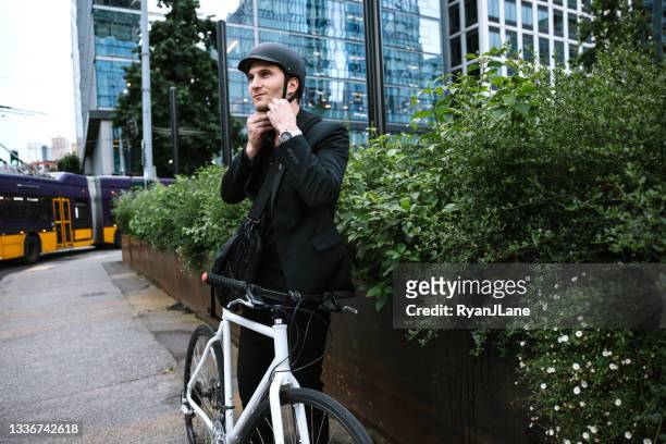 bike riding urban commuter putting on helmet - seattle city life stock pictures, royalty-free photos & images