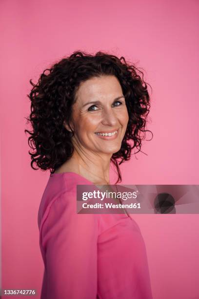 smiling businesswoman standing by pink background - lila stockfoto's en -beelden