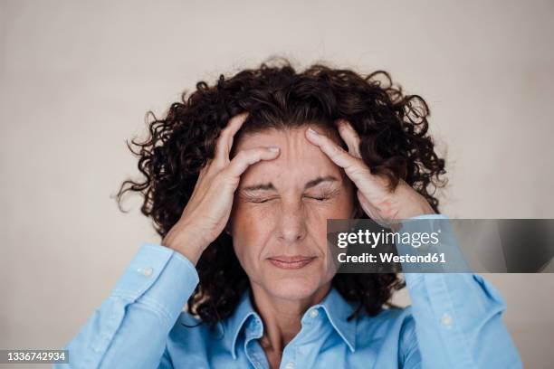 exhausted businesswoman grimacing with headache - headache stock-fotos und bilder