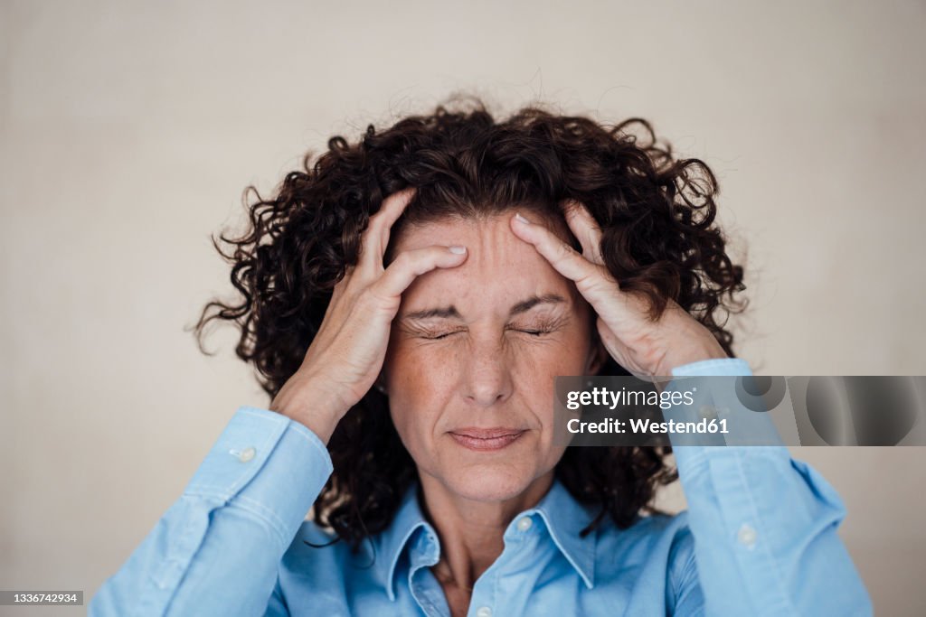 Exhausted businesswoman grimacing with headache