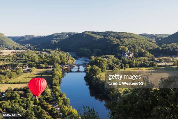 red hot air balloon flying over dordogne river - dordogne river stock pictures, royalty-free photos & images