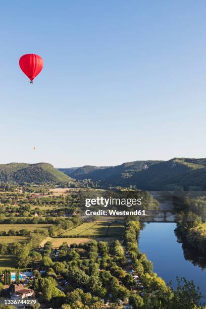 red hot air balloon flying against clear sky over dordogne river - périgord photos et images de collection