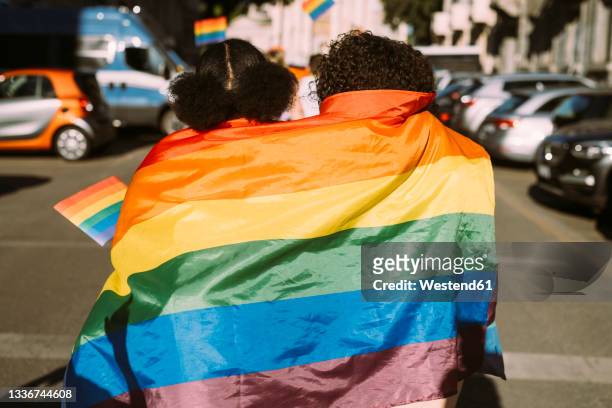 female friends wrapped in rainbow flag on sunny day - proud bildbanksfoton och bilder