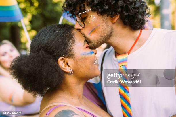 young man kissing woman on forehead - black women kissing white men stock pictures, royalty-free photos & images