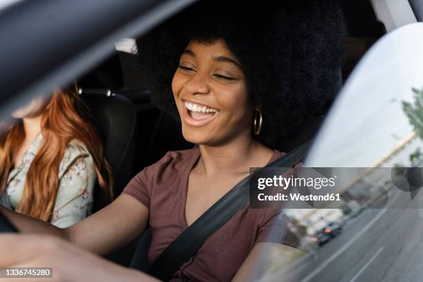 young woman laughing while driving car by female friend - friends inside car imagens e fotografias de stock