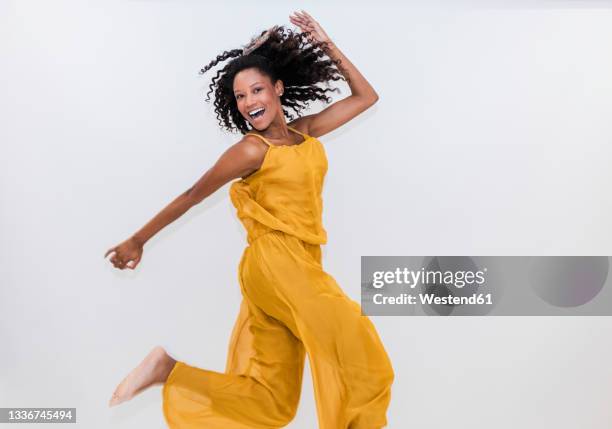 carefree woman dancing while jumping on white background - dancing white background stock pictures, royalty-free photos & images