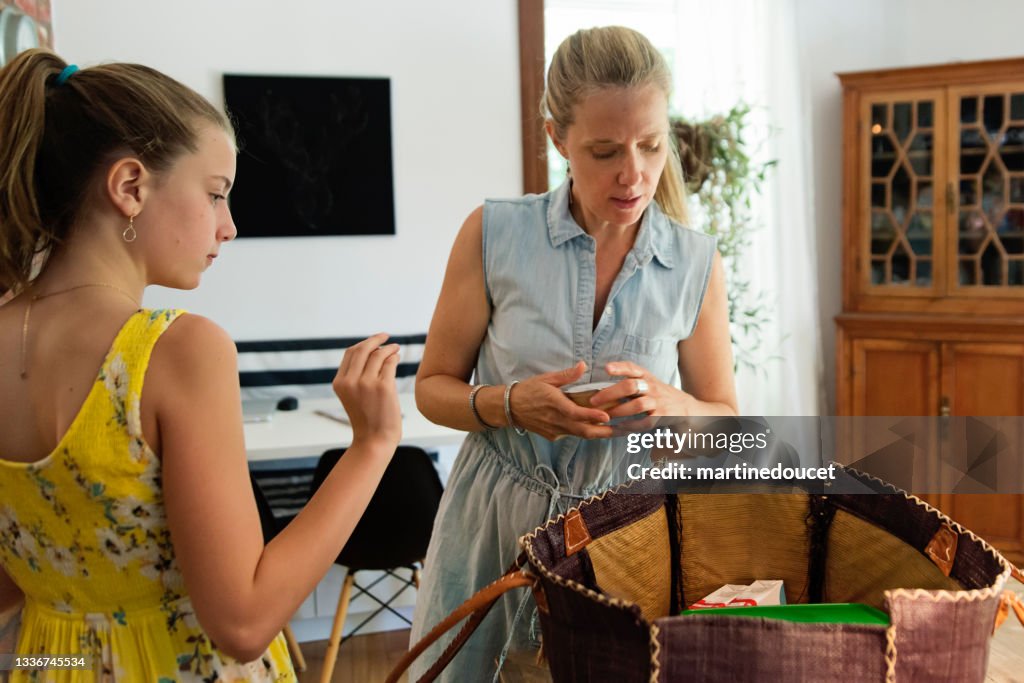 Mother and daughter packing lunch in picnic bag.