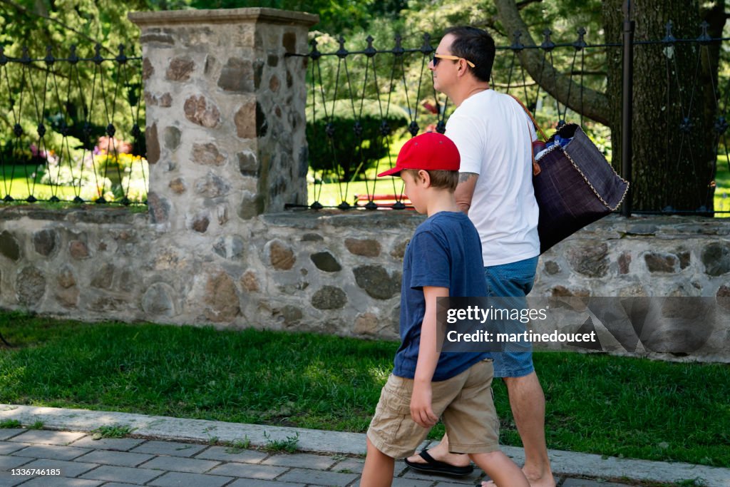 Padre e hijo caminando por una calle de un suburbio.