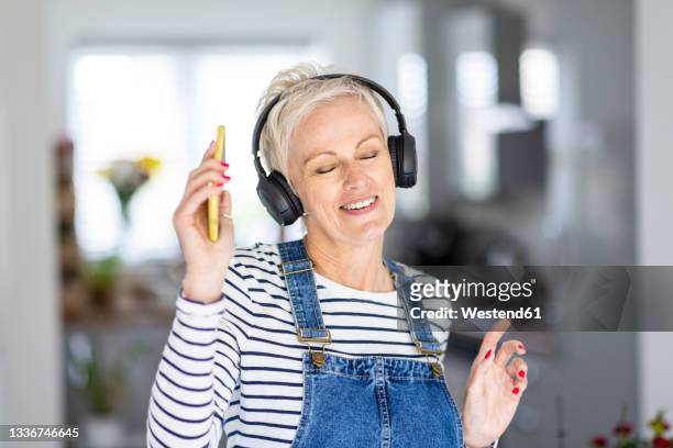 mature woman dancing while listening music at home - music headphone express stock pictures, royalty-free photos & images