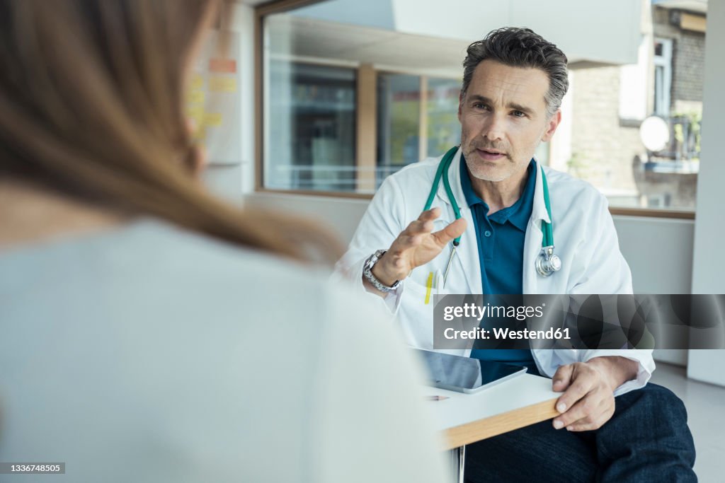 Male doctor explaining female patient while sitting in office