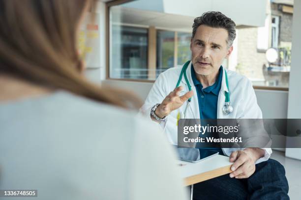 male doctor explaining female patient while sitting in office - doctor talking imagens e fotografias de stock