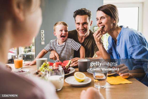 father and mother looking at daughter while having breakfast at home - mutter kind brot glücklich stock-fotos und bilder