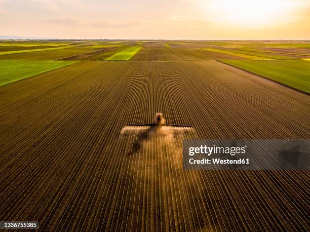 aerial view of tractor spraying soybean crops at sunset - farm machinery stock-fotos und bilder