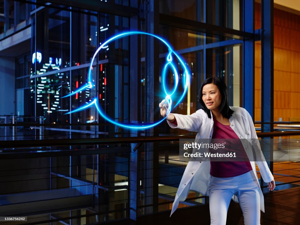 Mature female ophthalmologist light painting in laboratory at hospital