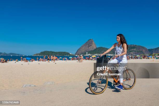 若い女性はプライア・ド・フラメンゴで自転車に乗る - フラミンゴビーチ ストックフォトと画像