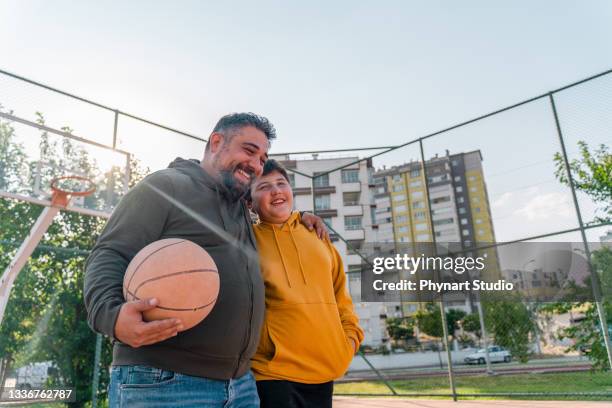 mature man and his son walking in the public park - basketball teenager stock pictures, royalty-free photos & images