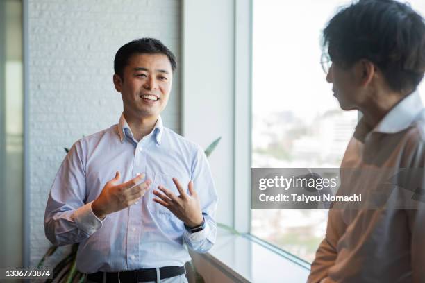 a man talking to a colleague during a break - asian discuss photos et images de collection