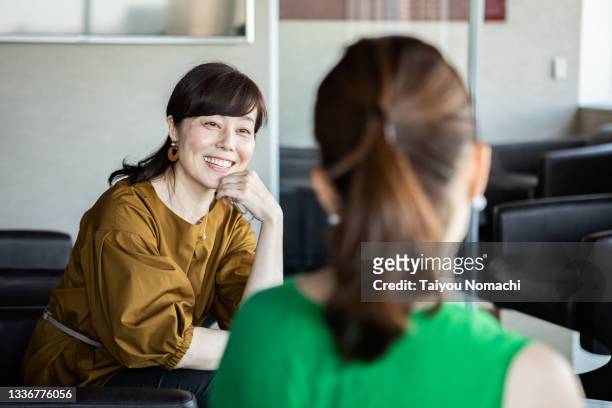 a woman talking to a colleague during a break - japanese woman stock pictures, royalty-free photos & images