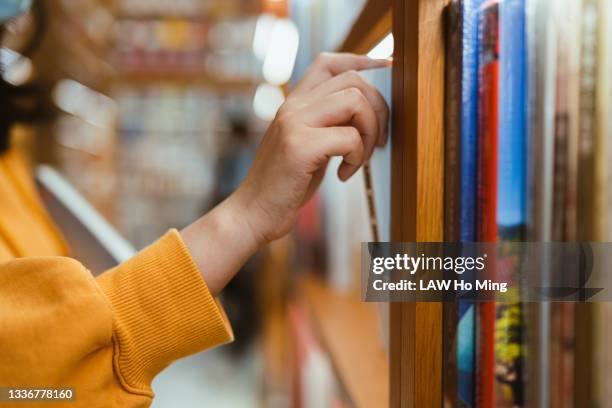 a hand takes out a book from the shelf - bookcase stockfoto's en -beelden