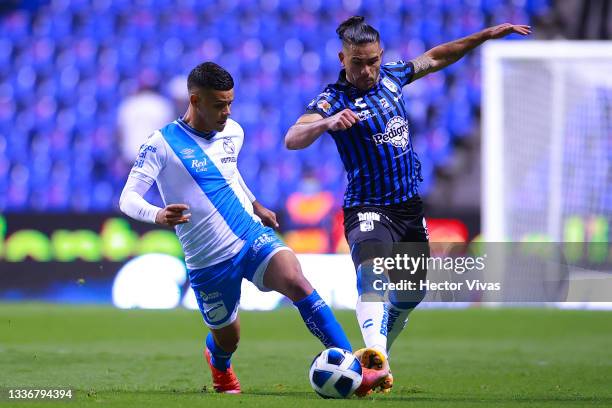 Maximiliano Araujo of Puebla battles for possesion with Jonathan Dos Santos of Queretaro during the 7th round match between Puebla and Queretaro as...