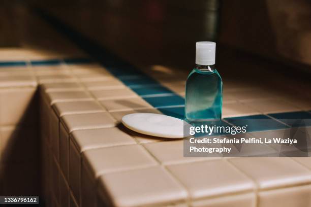 bar of soap and a travel size plastic bottle of liquid soap on a tiled bath tub surround. copy space. - douche savon photos et images de collection