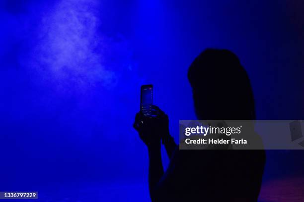 silhouette of woman holding a smartphone in live stream. - festival of arts celebrity benefit event stockfoto's en -beelden