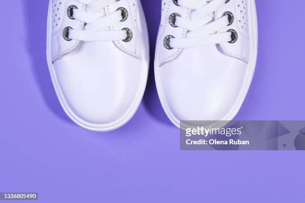 two pure white sneakers on violet background - paarse schoen stockfoto's en -beelden