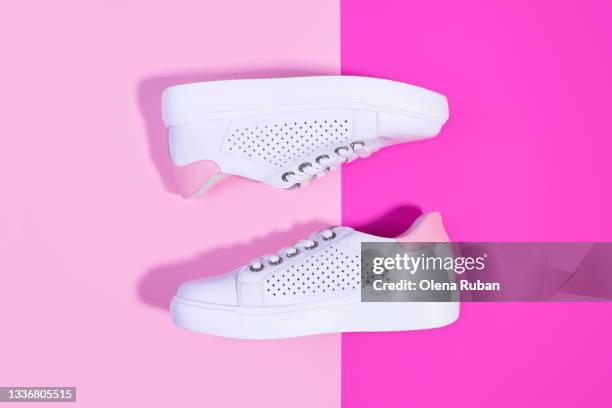 two pure white sneakers on a bicolor light and bright pink background - colorful shoes stock pictures, royalty-free photos & images