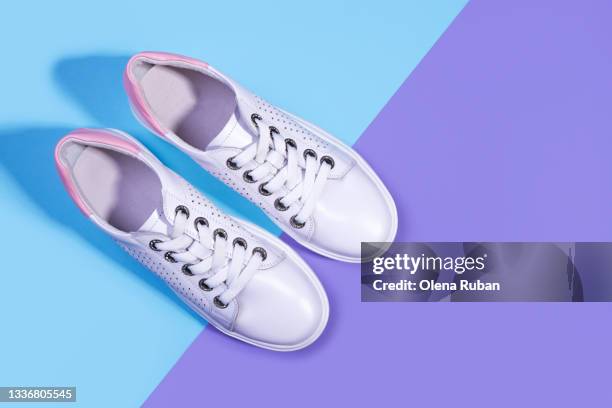 white sneakers on blue and violet background - paarse schoen stockfoto's en -beelden