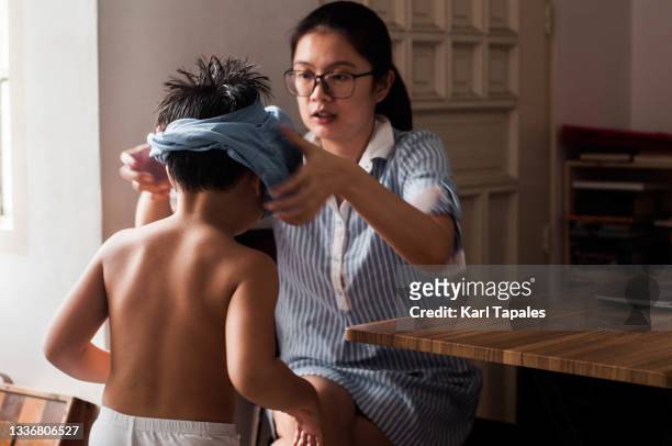 a young southeast asian mother is assisting her son getting ready for distant learning using laptop at home - stay home - fotografias e filmes do acervo