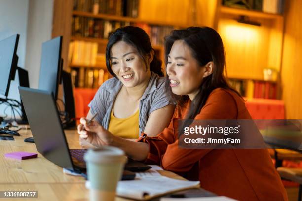 asian business women engaging a work discussion at a coworking space. - southeast stock pictures, royalty-free photos & images