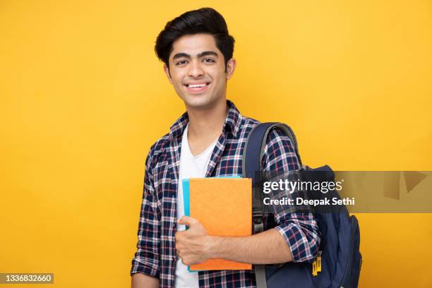 männlicher teenager-student in gelbem hintergrund stockfoto - indian college students stock-fotos und bilder