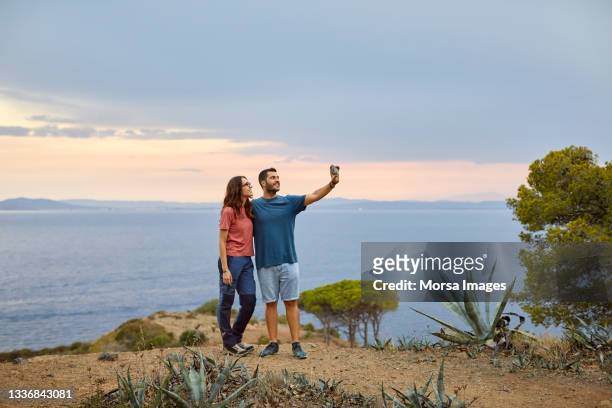 man taking selfie with woman on cliff - couple standing full length stock pictures, royalty-free photos & images