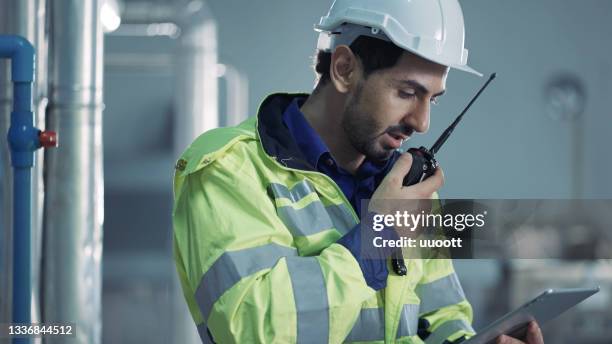 worker holding digital tablet in hand talking on walkie-talkie - walkie talkie stock pictures, royalty-free photos & images