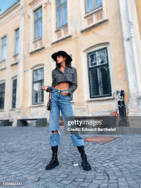 Jacqueline Barth wears a black felt / wool hat, a black and white houndstooth print pattern cropped long sleeves jacket, blue faded denim high waist...