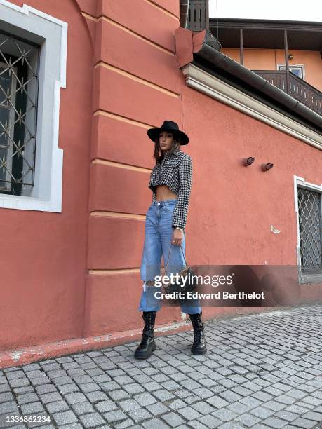 Jacqueline Barth wears a black felt / wool hat, a black and white houndstooth print pattern cropped long sleeves jacket, blue faded denim high waist...