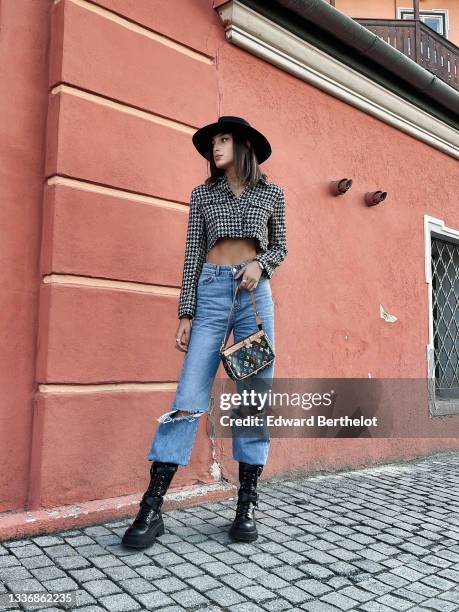 Jacqueline Barth wears a black felt / wool hat, a black and white houndstooth print pattern cropped long sleeves jacket, blue faded denim high waist...