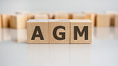 AGM word is made of wooden building blocks lying on the grey table, concept