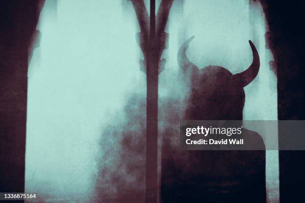 a dark fantasy concept . of a mysterious devil woman with horns, looking out of a window in an old building, with a blurred, abstract edit. - teufel stock-fotos und bilder