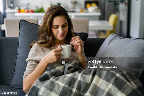 woman relaxing at home on the sofa drinking a cup of tea - blanket stock pictures, royalty-free photos & images