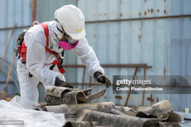 safety is our top priority. worker wearing full body protective clothing while working with the asbestos roof tiles. - asbestos stock pictures, royalty-free photos & images