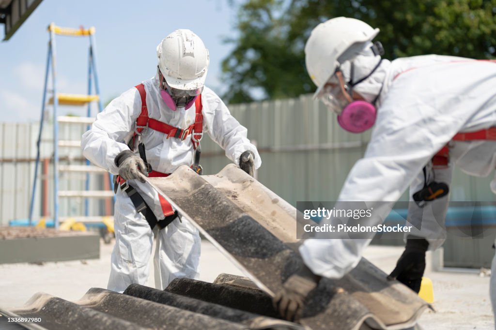 Safety is our top priority. Workers wearing full body protective clothing while working with the asbestos roof tiles.
