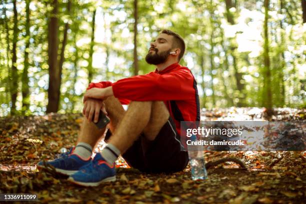 young man with bluetooth headphones resting in forest - deep relaxation stock pictures, royalty-free photos & images