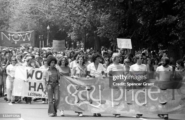 View of the large crowd, some of whom are holding up handmade signs and banners, participating in a gay and lesbian pride parade in the Back Bay...