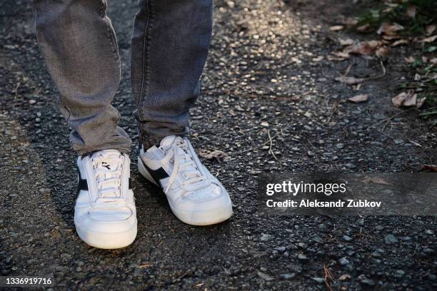the legs of a guy or a man in old clean modern sneakers and jeans. a teenager in sports shoes is standing or walking on the sidewalk or asphalt. a fashionable and stylish lifestyle. a copy of the text space. - old man feet stock pictures, royalty-free photos & images