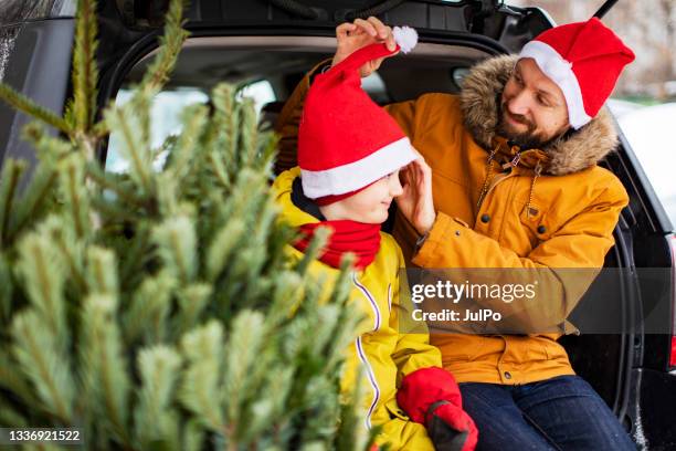 vater und sohn kaufen weihnachtsbaum - nikolausmütze stock-fotos und bilder
