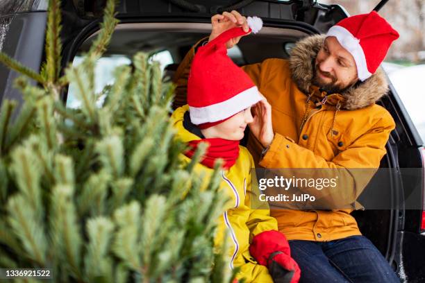 father and son buying christmas tree - santa hat stock pictures, royalty-free photos & images